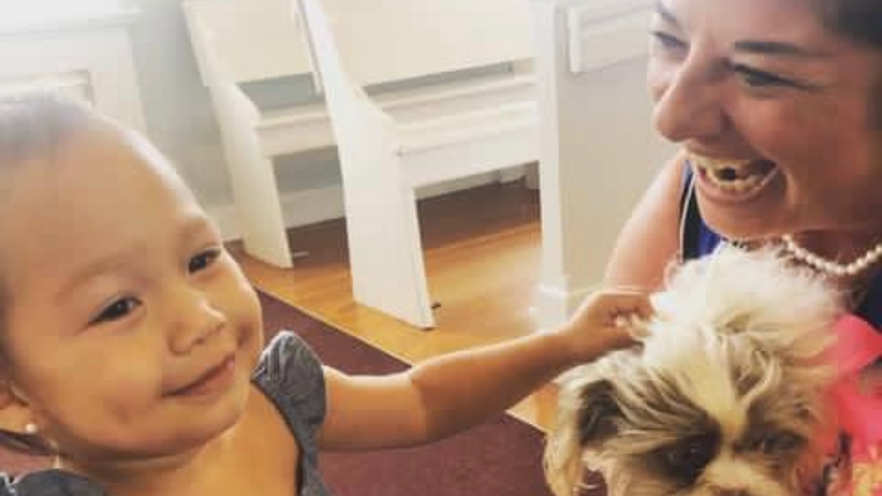 Aunty Cindy smiling with a little dog and a young girl inside a church